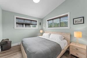 a bedroom with a large bed and two windows at Wild Beauty - Oceanview - Pet Friendly - sleep 2 in Port Renfrew