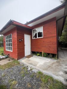 a small red house with a white door at Cabaña A & M in Chaitén