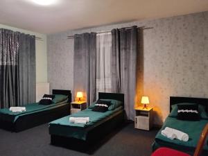 two beds in a room with two lamps and curtains at Villa Varzob lll in Warsaw