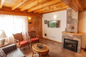 a living room with a fireplace and a couch and chairs at Apart del Faldeo in San Martín de los Andes