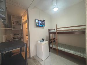 a room with two bunk beds and a tv on the wall at Mini Studio Villaggio juquehy in São Sebastião