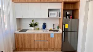 a small kitchen with a refrigerator and a microwave at Nuevo y moderno departamento Quito Norte in Quito