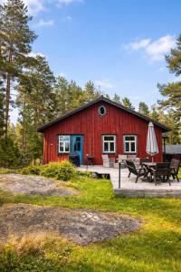 a red barn with a picnic table and an umbrella at Private archipelago villa with large property in Pargas