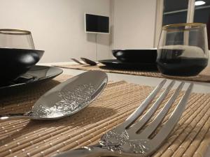 a table with a fork and spoon and a glass of wine at Central Living Brugg - Studio 11 in Brugg