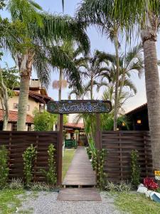 a wooden pathway leading to a house with palm trees at Hospedaria aconchego master in Garopaba