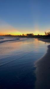 a view of a beach with the sun setting at Hospedaria aconchego master in Garopaba