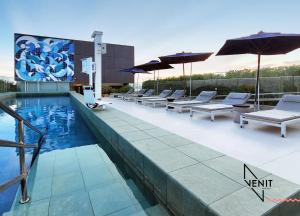 a pool with lounge chairs and umbrellas on a building at Venit Barra Hotel in Rio de Janeiro