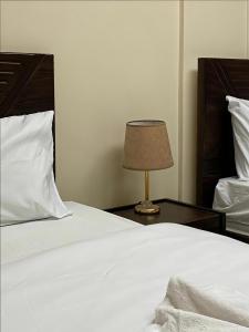 a white bed with a lamp on a table at The Cozy Twin Room in Cairo