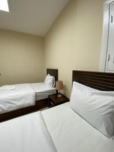 a bedroom with two beds with white sheets and a lamp at The Cozy Twin Room in Cairo