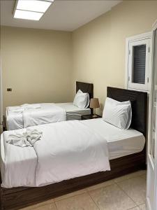 two beds in a room with white sheets and pillows at The Cozy Twin Room in Cairo