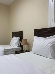 a bedroom with two beds with white sheets and a lamp at The Cozy Twin Room in Cairo