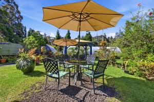 a table and chairs with a yellow umbrella at Volcano Artist Cottage in Volcano