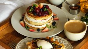 a table with two plates of food with a stack of pancakes at Tau House in Guatapé
