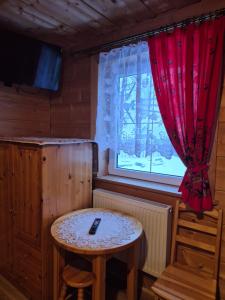 a small table in a room with a window at Miodowa Chatka in Brzegi