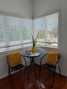 a table and two chairs in a room with two windows at Irina's bnb in Auckland