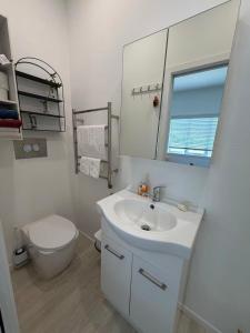 a white bathroom with a toilet and a sink at Irina's bnb in Auckland