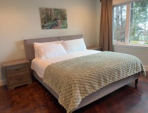 a bed in a bedroom with a window and a bedspread at Large ocean view family retreat in Comox