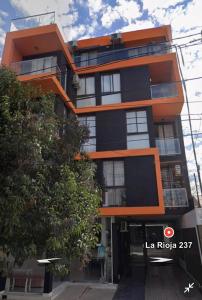 an orange and black building with a tree at Dpto en la costa in Villa María