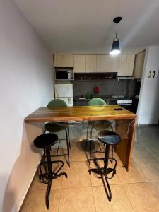 a kitchen with a wooden counter with four bar stools at Dpto en la costa in Villa María