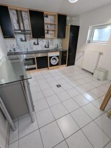 a white tiled kitchen with a sink and a dishwasher at Apartment Kraft in Aßlar