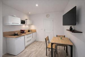 a kitchen with white cabinets and a table with chairs at Tiny House Marie in Châtellerault