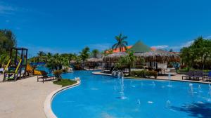 a pool at a resort with a slide and water fountain at La Ensenada Beach Resort in Tela