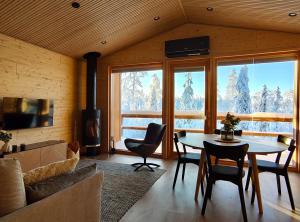 a living room with a table and chairs and a fireplace at Peaceful Cabin with Hot Tub and Nature Views, Villa Lakeside Ruka in Ruka