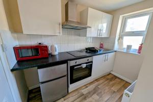 a small kitchen with white cabinets and a red microwave at Spacious Studio with Private Kitchen and Bathroom in Hounslow