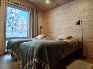 two beds in a room with a window at Peaceful Cabin with Hot Tub and Nature Views, Villa Lakeside Ruka in Ruka