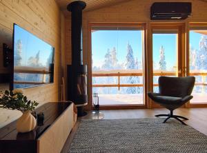 a living room with a fireplace and a chair and windows at Peaceful Cabin with Hot Tub and Nature Views, Villa Lakeside Ruka in Ruka