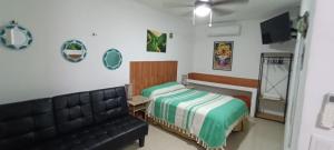 a bedroom with a bed and a leather couch at Depa los corales 3 in Mezcales