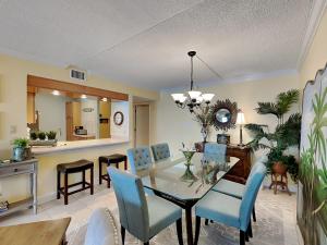 a dining room with a glass table and blue chairs at Island Echos #3K in Fort Walton Beach +21 photos