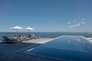 a swimming pool with chairs and umbrellas next to the ocean at Playa Vik Jose Ignacio in José Ignacio