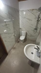 a white bathroom with a toilet and a sink at Veranda Guest House in Berat