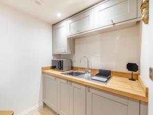 a kitchen with white cabinets and a sink at Haybale Barn in Chatton