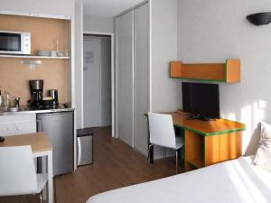 a small room with a desk and a kitchen at Aparthotel Adagio Access Paris Maisons-Alfort in Maisons-Alfort