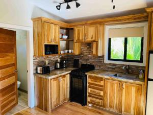 a kitchen with wooden cabinets and a black stove at The Flying Toucan Beach Rentals in Placencia