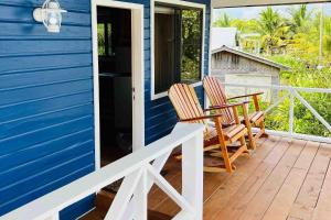 two chairs on the front porch of a blue house at The Flying Toucan Beach Rentals in Placencia