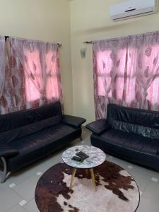 a living room with two black couches and a table at VOYALUX BENIN Appartement in Cotonou +3 photos
