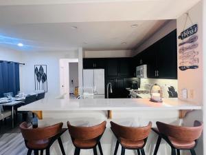 a kitchen with a white counter and brown chairs at Stylish & Fully Renovated Home! in Oxnard +65 photos