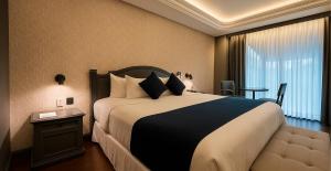 ein Hotelzimmer mit einem großen Bett und einem Tisch in der Unterkunft Hive Nápoles by G Hotels in Mexiko-Stadt
