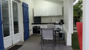 a kitchen with white cabinets and a table and chairs at LE DOMAINE de L'HYLODE in Sainte-Anne
