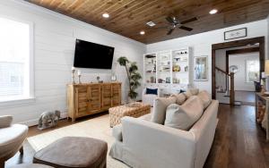 a living room with white walls and a flat screen tv at Deja Blue by Oversee 30A in Santa Rosa Beach