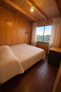 a bedroom with a bed and a large window at Cabañas Mc Chelo Pelluhue in Pelluhue