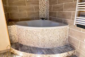 a bath tub in a bathroom with a tile wall at L'instant Douceur in Riorges +24 photos