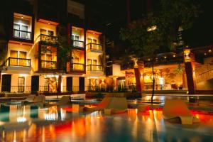 a pool with chairs in front of a building at night at RAI ATRIUM SUITES HOTEL - Cauayan in Cauayan City