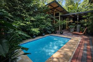 a swimming pool in the middle of a garden at Exōtico Beach Hotel in Puerto Viejo