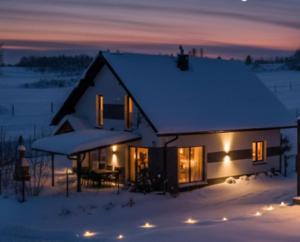 a house covered in snow at night with lights at Chwilo Trwaj dom z jacuzzi, sauną i kominkiem z widokiem na góry Korbielów Pilsko in Korbielów
