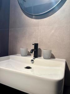 a bathroom sink with two cups on top of it at DESIGNBUTZE by BUTZENFLOTTE Grömitz - Beach Loft & Meerblick in Grömitz