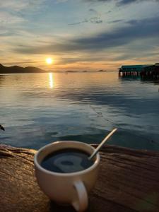 a cup of coffee sitting on a table next to the water at Chill House kohchang in Ban Bang Bao +3 photos